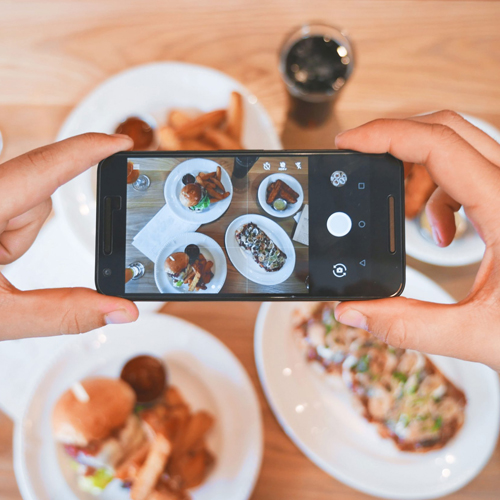 Une personne est en train de prendre en photo des plats de nourriture avec un smartphone